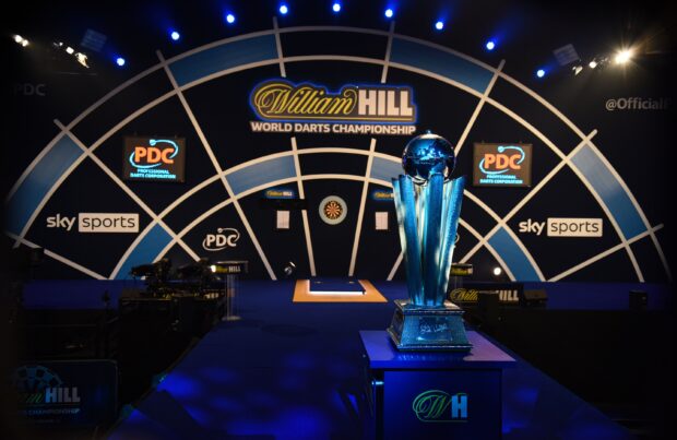 The World Darts Championship trophy is displayed on stage with dartboards in the background, 2K Desktop Wallpaper