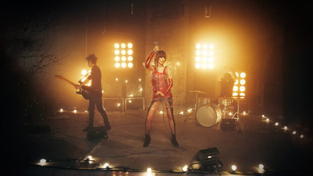 The Yeah Yeah Yeahs are performing on a stage with bright lights, HD Desktop Wallpaper
