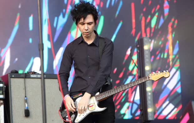 A guitarist performing live on stage with a colorful background featuring Yeah Yeah Yeahs, HD Desktop Wallpaper