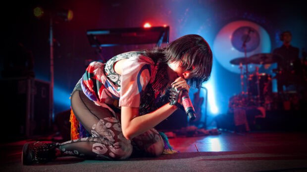 The lead singer of Yeah Yeah Yeahs performing intensely on stage during a concert, HD Desktop Wallpaper