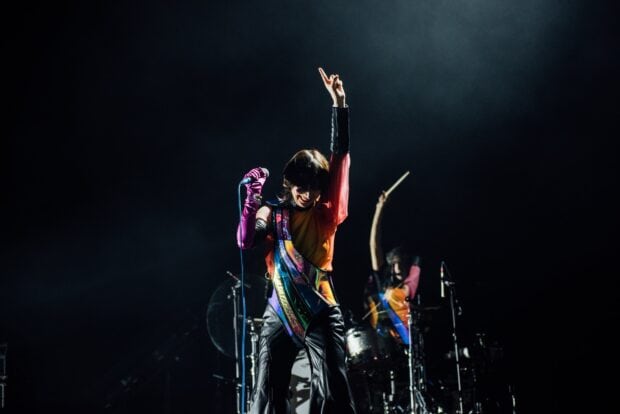 The lead singer of Yeah Yeah Yeahs is performing with vibrant attire and a raised hand, HD Desktop Wallpaper