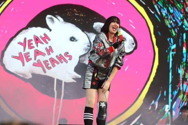 The lead singer of Yeah Yeah Yeahs performs with vibrant backdrop, 2K Desktop Wallpaper