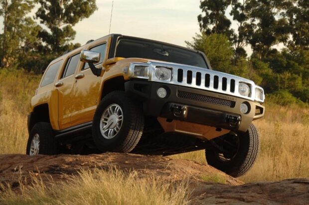 A yellow Hummer H3 is driving over rocky terrain in a natural setting, HD Desktop Wallpaper