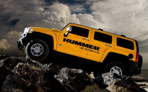 A yellow Hummer H3 is driving over large rocks under a cloudy sky, HD Desktop Wallpaper