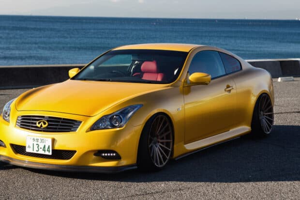 A yellow Infiniti G37 is parked near the ocean with a clear blue sky, HD Desktop Wallpaper