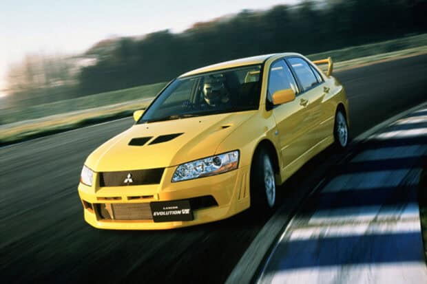 A yellow Lancer Evo is racing on a curving track with motion blur visible, HD Desktop Wallpaper