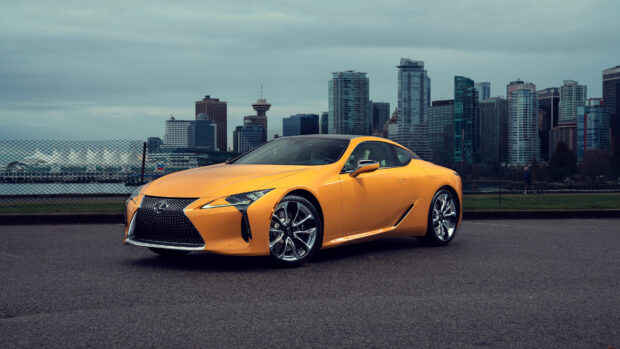 A yellow Lexus LC sports car is parked on the road with a city skyline in the background, 4K Desktop Wallpaper