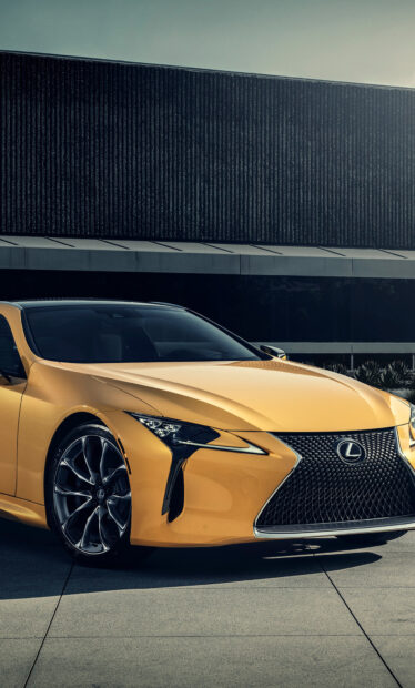 A yellow Lexus LC sports car is parked on a concrete driveway in front of a contemporary black and gray building, HD Phone Wallpaper