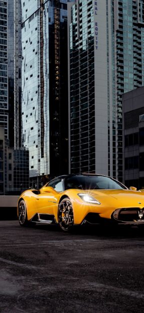 A yellow Maserati MC20 parked on an urban rooftop surrounded by tall skyscrapers, 2K Mobile Wallpaper