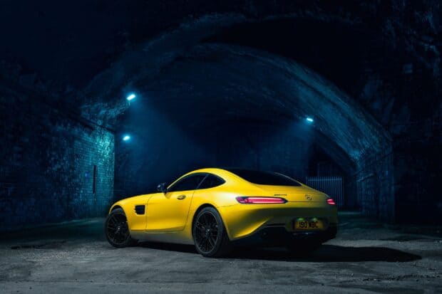 A yellow Mercedes Benz AMG GT is illuminated under blue lights in a dark tunnel, 2K Desktop Wallpaper