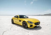A yellow Mercedes Benz AMG GT is parked on a dry salt flat under a clear blue sky, 2K Desktop Wallpaper