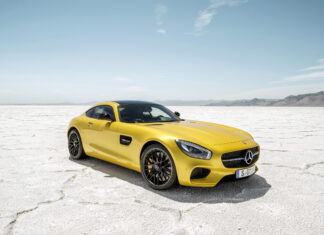 A yellow Mercedes Benz AMG GT is parked on a dry salt flat under a clear blue sky, 2K Desktop Wallpaper