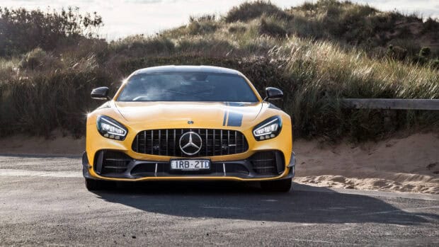 A yellow Mercedes Benz Amg Gt is parked on a road with sand dunes and grass in the background, 4K Desktop Wallpaper