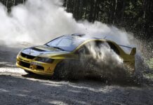 A yellow Lancer Evo racing aggressively on a forest gravel track kicking up dust, HD Desktop Wallpaper
