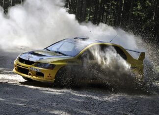 A yellow Lancer Evo racing aggressively on a forest gravel track kicking up dust, HD Desktop Wallpaper