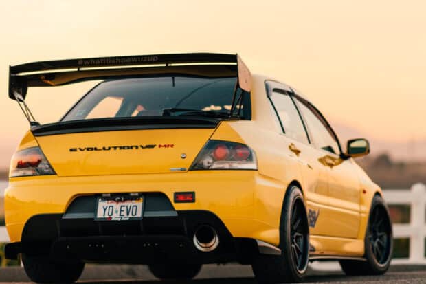 A yellow Mitsubishi Lancer Evo is parked with detailed decals and a large rear spoiler, HD Desktop Wallpaper