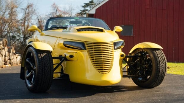 A yellow Plymouth Prowler is parked on a driveway near a red barn in this image, HD Desktop Wallpaper