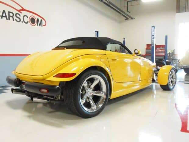 A yellow Plymouth Prowler is displayed in a bright showroom with shiny chrome wheels, HD Desktop Wallpaper