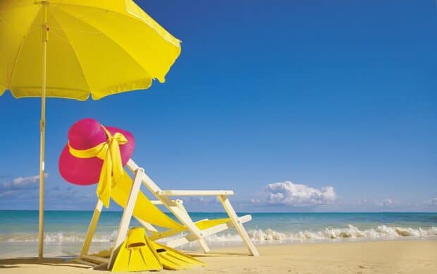 A yellow beach umbrella and chair stand on the sandy shore near the ocean, 2K Desktop Wallpaper