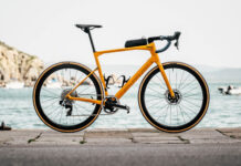 A yellow Bmc bike stands on a stone pier near the water and boats, HD Desktop Wallpaper