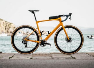 A yellow Bmc bike stands on a stone pier near the water and boats, HD Desktop Wallpaper