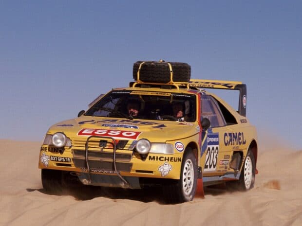 A yellow rally raid car speeding across desert dunes during a race, HD Desktop Wallpaper