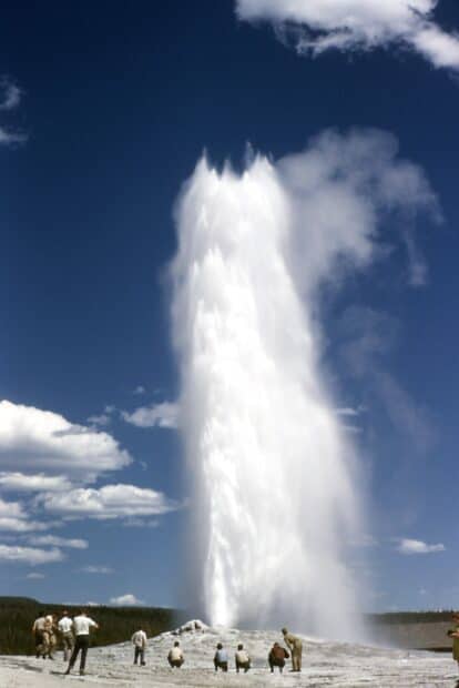 Tourists observe a geyser eruption in Yellowstone National Park under a clear sky, HD Desktop Wallpaper