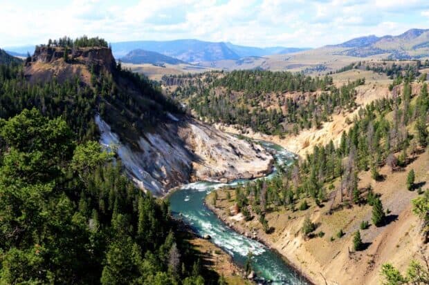 A winding river flows through the forest and rocky cliffs in Yellowstone National Park, HD Desktop Wallpaper