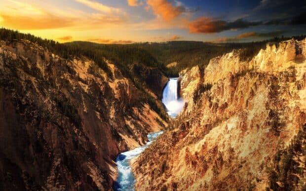 A stunning waterfall flows through rocky cliffs in Yellowstone National Park, 2K Desktop Wallpaper