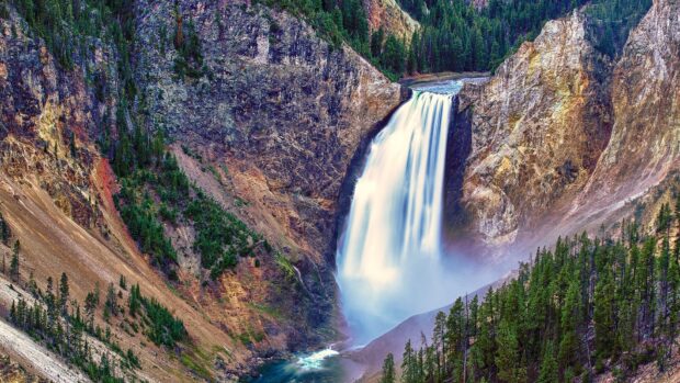 A stunning waterfall in Yellowstone National Park surrounded by rocky cliffs and forest, HD Desktop Wallpaper