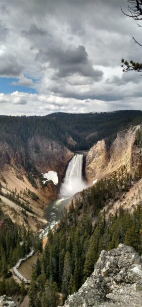 Yellowstone National Park features a large waterfall amidst trees and rocky cliffs, 2K Mobile Wallpaper