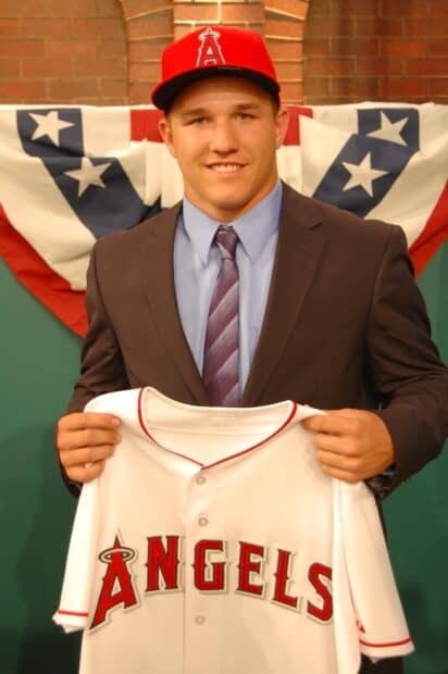 A young man proudly holding a Los Angeles Angels jersey while smiling at the camera, HD Phone Wallpaper