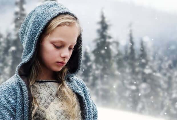 A young girl in a blue hooded sweater stands in a snowy forest environment, HD Desktop Wallpaper