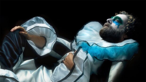 A man with colorful clown makeup wearing a ruffled costume in a dramatic pose, HD Desktop Wallpaper