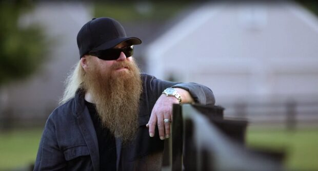 A man with a long beard and sunglasses stands by a fence in a rural setting featuring Zz Top wallpapers, HD Desktop Wallpaper