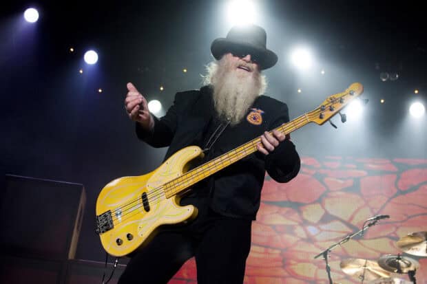 A musician from Zz Top playing an electric bass guitar on stage with dramatic lighting, HD Desktop Wallpaper
