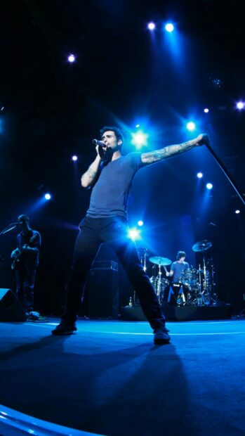Adam Levine is singing passionately on stage under blue lights, HD Mobile Wallpaper
