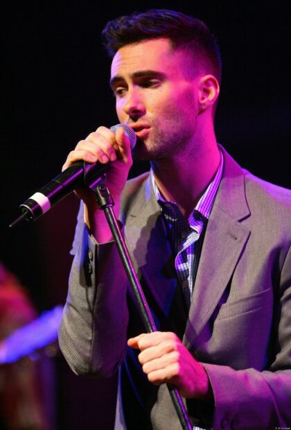 Adam Levine Wallpapers shows the singer wearing a suit while performing on stage, 2K Desktop Wallpaper
