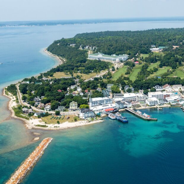 The aerial view captures Mackinac Island harbor surrounded by greenery and buildings, HD Desktop Wallpaper