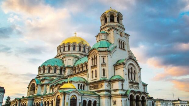 The Alexander Nevsky Cathedral stands prominently under the cloudy sky in Bulgaria with golden and green domes