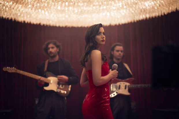 Ana De Armas stands holding a microphone while two musicians play guitars behind her, HD Desktop Wallpaper