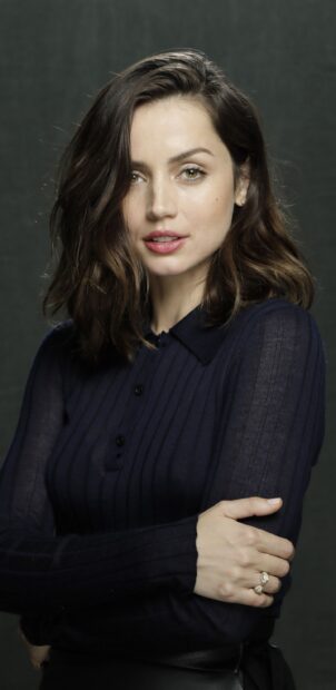 Ana De Armas is seen wearing a navy sweater with her arms crossed against a dark backdrop, 2K Phone Wallpaper