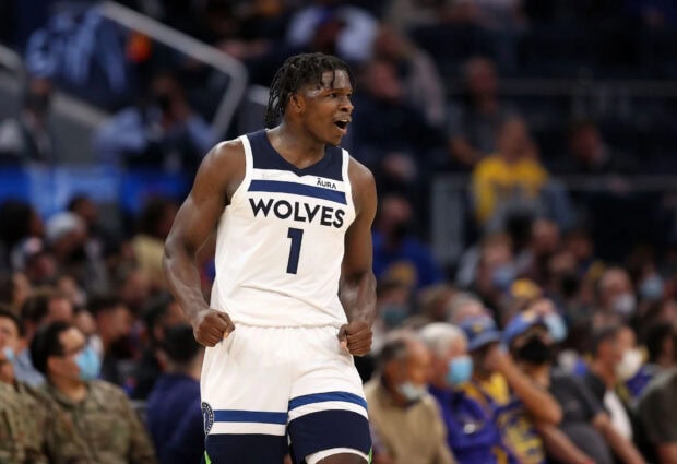 Anthony Edwards celebrating on the basketball court wearing a Wolves jersey in an intense game