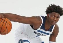 Anthony Edwards holding a basketball in a Wolves uniform in a dribbling pose
