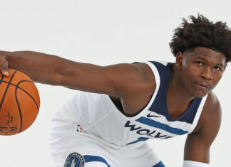 Anthony Edwards holding a basketball in a Wolves uniform in a dribbling pose