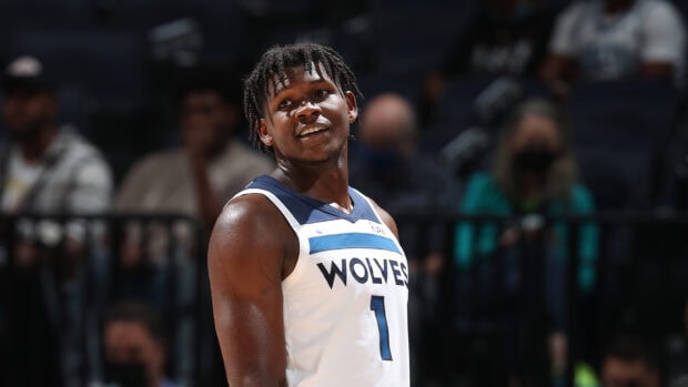 Anthony Edwards in a Wolves basketball jersey smiling during a game in an arena