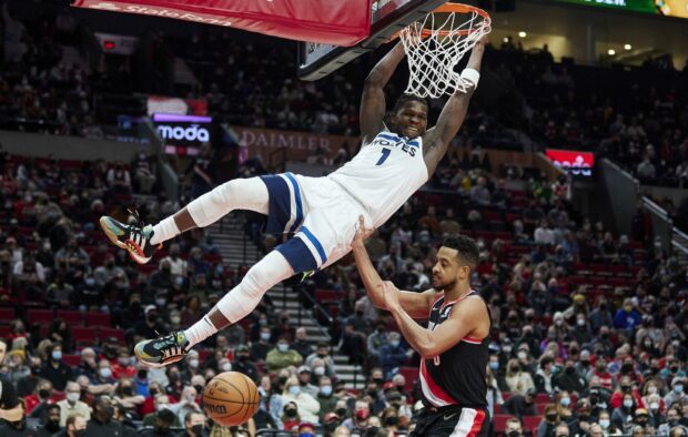 Anthony Edwards jumping to dunk the basketball during the game in a Wolves uniform