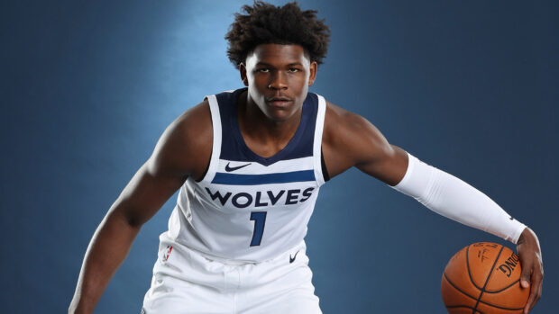 Anthony Edwards wearing a Wolves jersey holding a basketball in a defensive stance