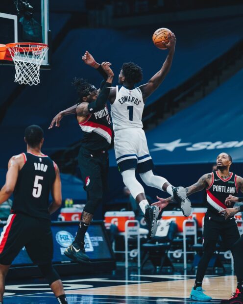Anthony Edwards jumping to score in a basketball game against multiple defenders