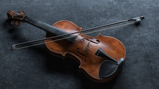 An antique wooden violin with a bow rests on a dark textured surface in this violin wallpapers, HD Desktop Wallpaper